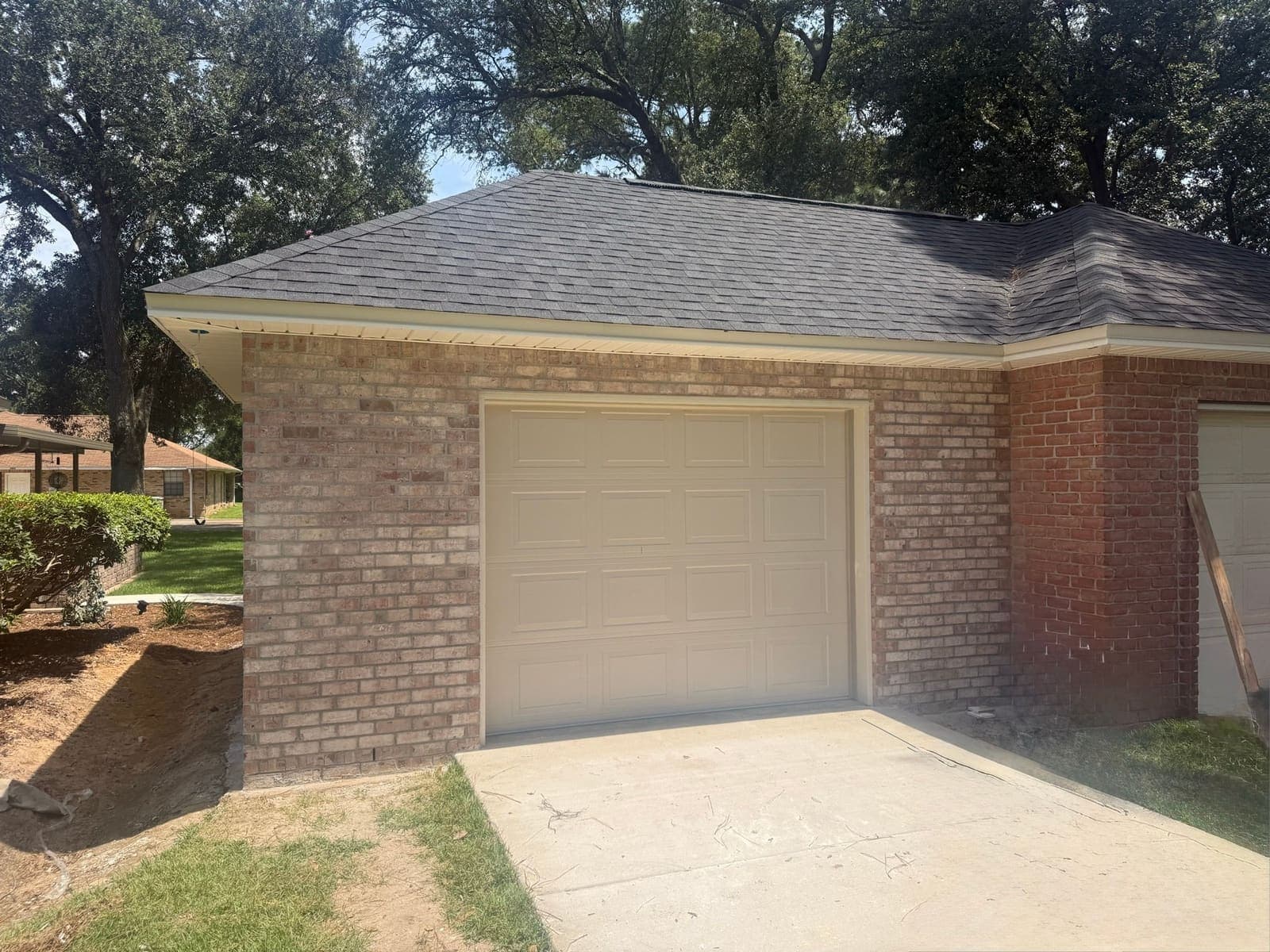 The finished brick garage with its door fitted and the concrete apron poured out to the drive