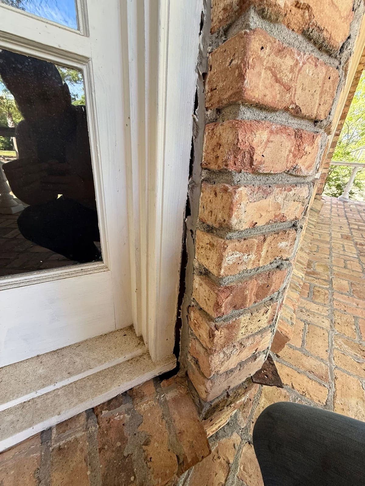 Vertical crack separating the brick column from the window frame before repair