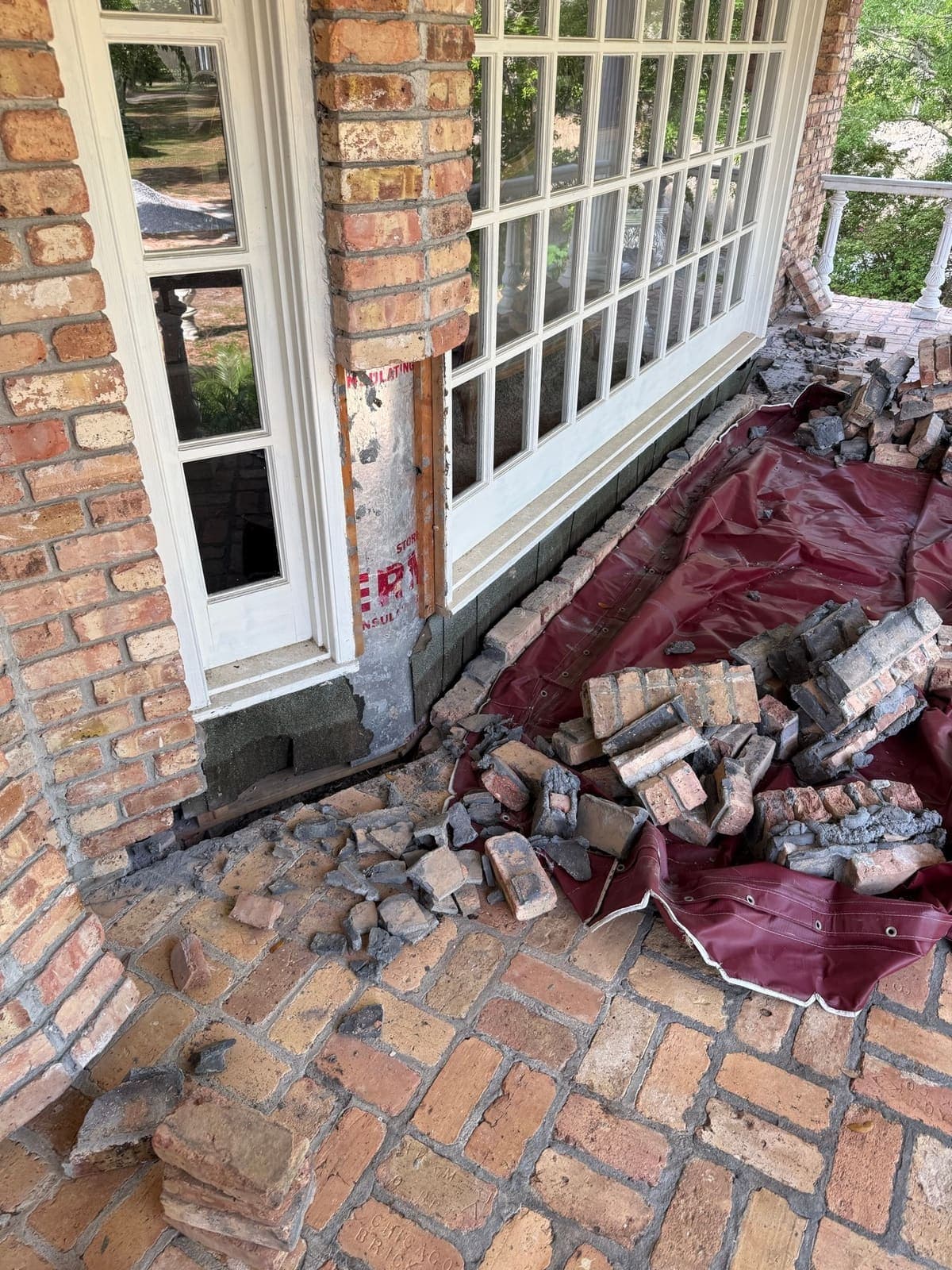 Failed brick removed from beneath the window and stacked on a tarp on the porch floor
