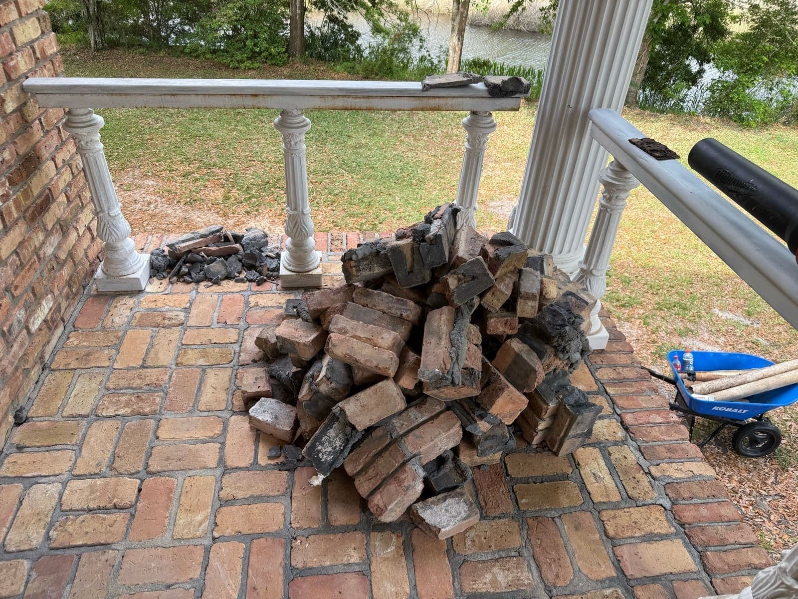 Original brick cleaned and stacked for reuse beside the porch columns