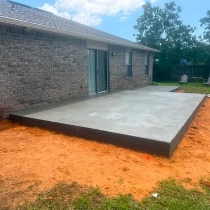 Finished concrete patio in the same spot behind the brick home, formed with a clean edge