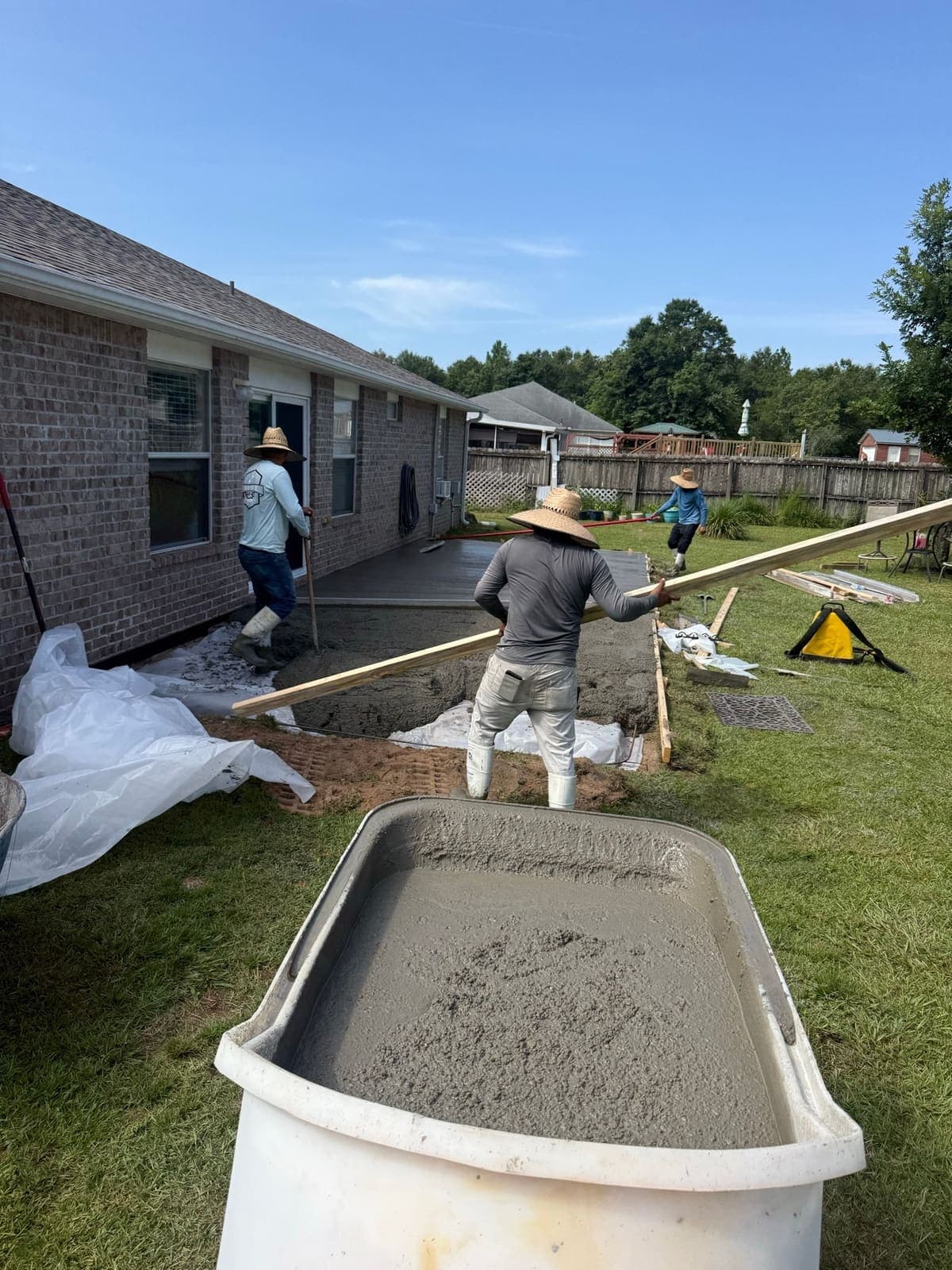 Concrete being placed and screeded between the forms behind the house