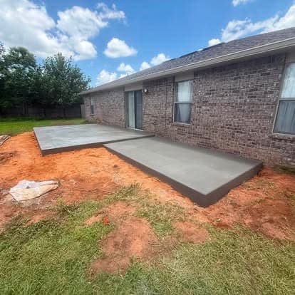 Finished concrete patio and connecting walkway behind a brick home