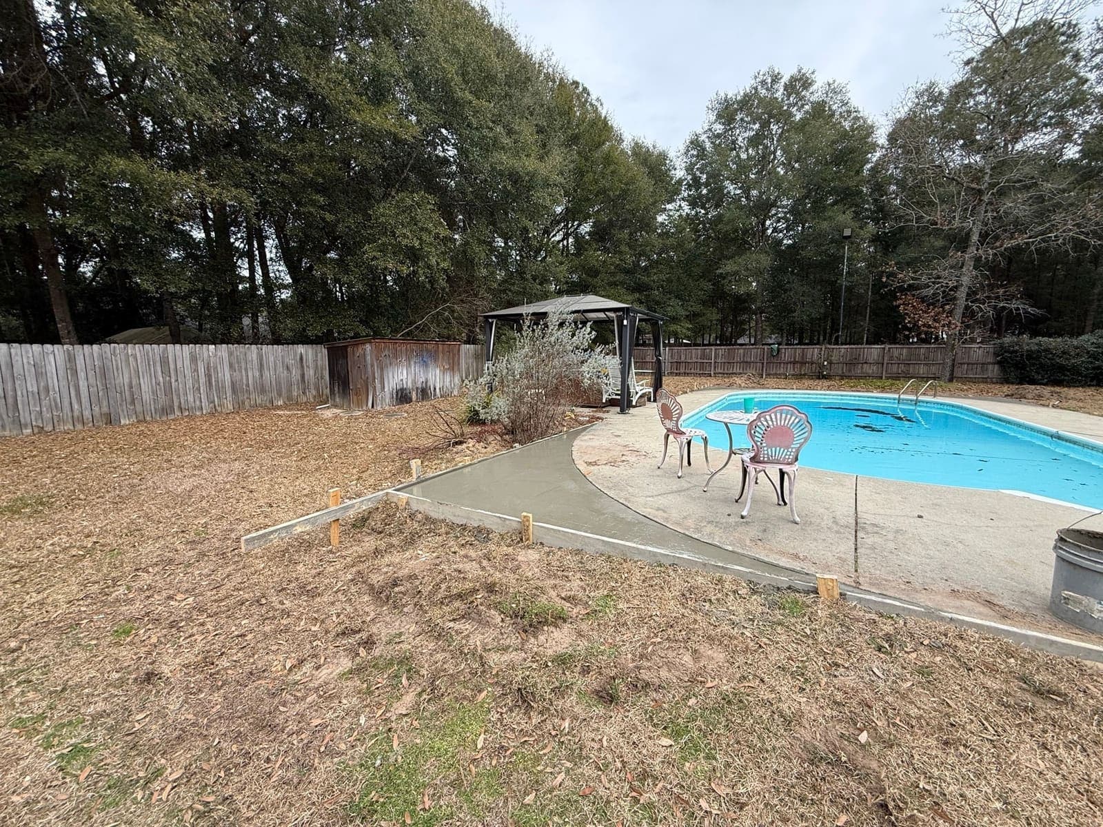 The same view after the pour, with the new wider concrete deck finished around the pool