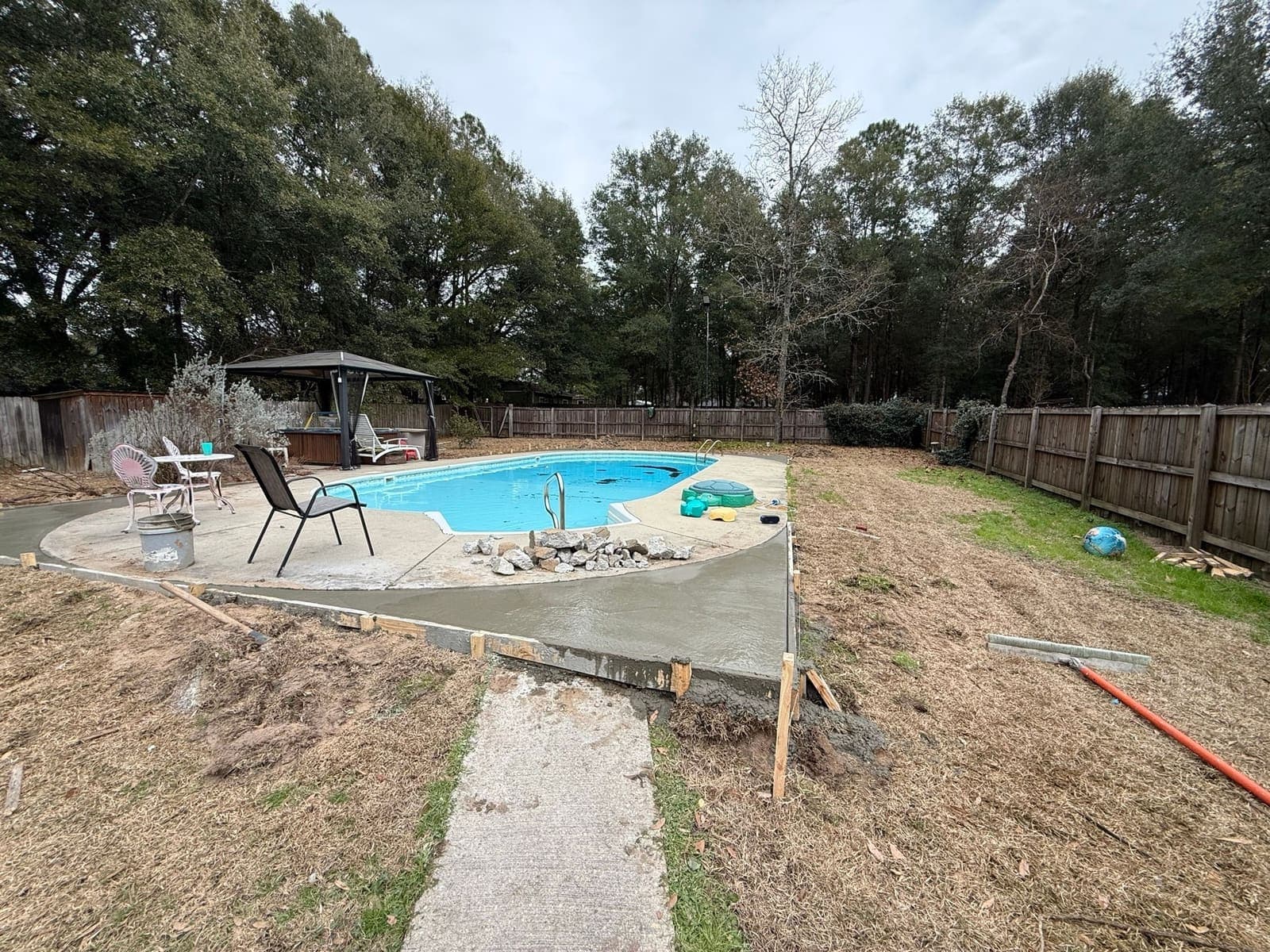 Pool surround with the broken deck section removed, forms set and bare ground where the new deck will go