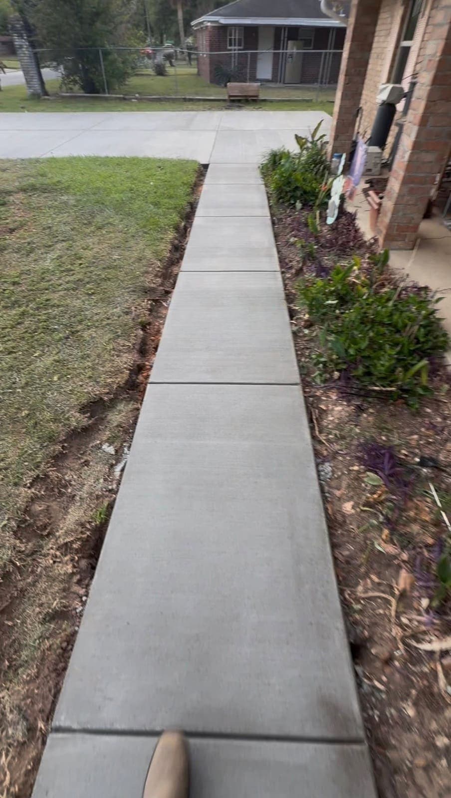 New concrete walkway alongside the house connecting the driveway to the entry