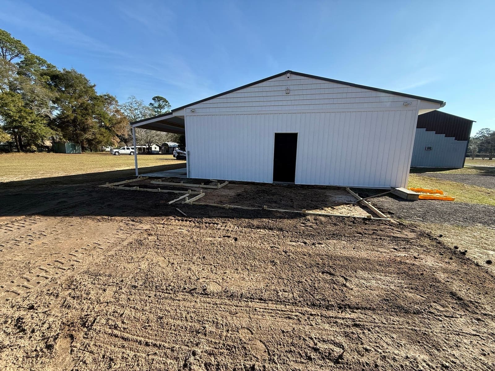 The new metal building sitting in bare graded dirt with walkway forms set out